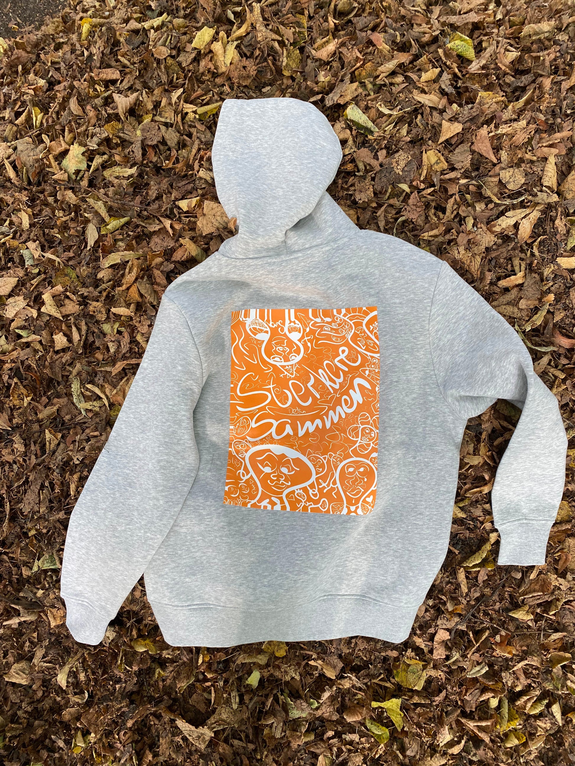 Sterkere sammen hoodie i grå. Motivet på ryggen er orange og laget av kunstneren Pang.start. Motivet er inspirert av kunstnerens tolkning av mental helse.